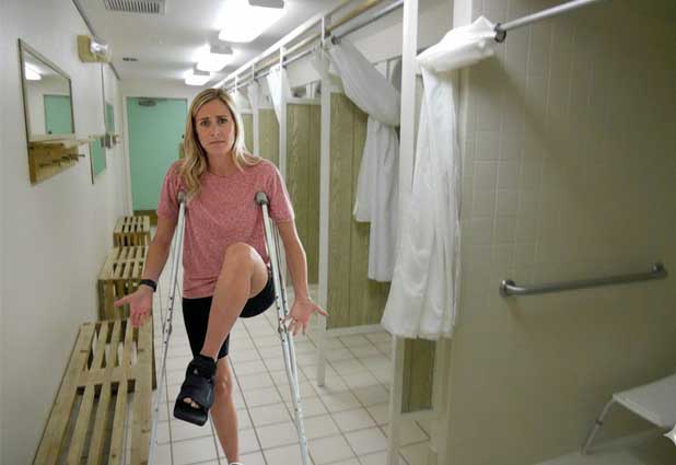 College student on crutches navigating a dorm style shower room with a walking boot