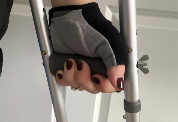 Close up of a hand gripping an underarm crutch with a padded glove.