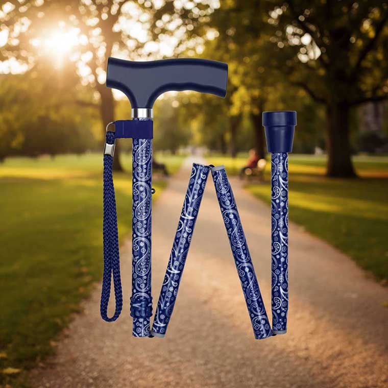 Cool Crutches folding walking stick in teal, fully unfolded and upright on a paved park path with greenery behind it