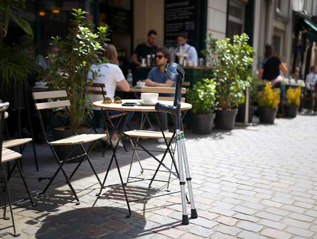 Cool Crutches Majestick forearm crutches leaning against an outdoor café table, silver diamante finish visible.