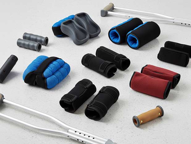 Close up of padded crutch handles and underarm cushions in different styles arranged on a clinic floor.